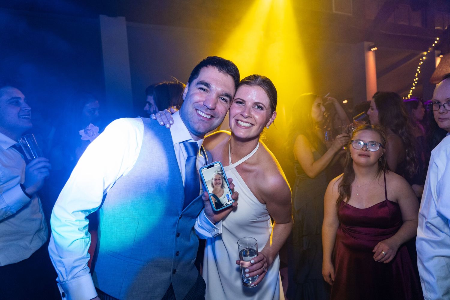 Party guests dancing under dramatic blue and yellow stage lighting.