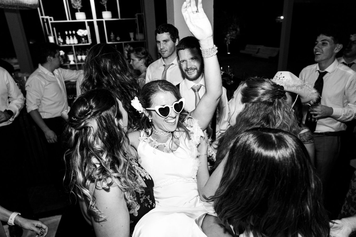 Wedding guests dancing and celebrating enthusiastically on a crowded dance floor at a reception party.