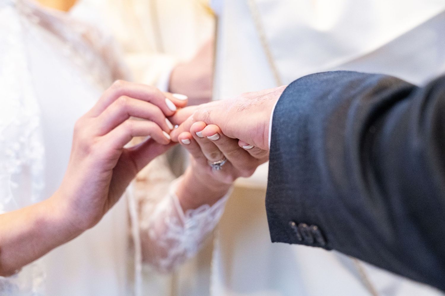 Close-up of hands exchanging wedding rings during ceremony.