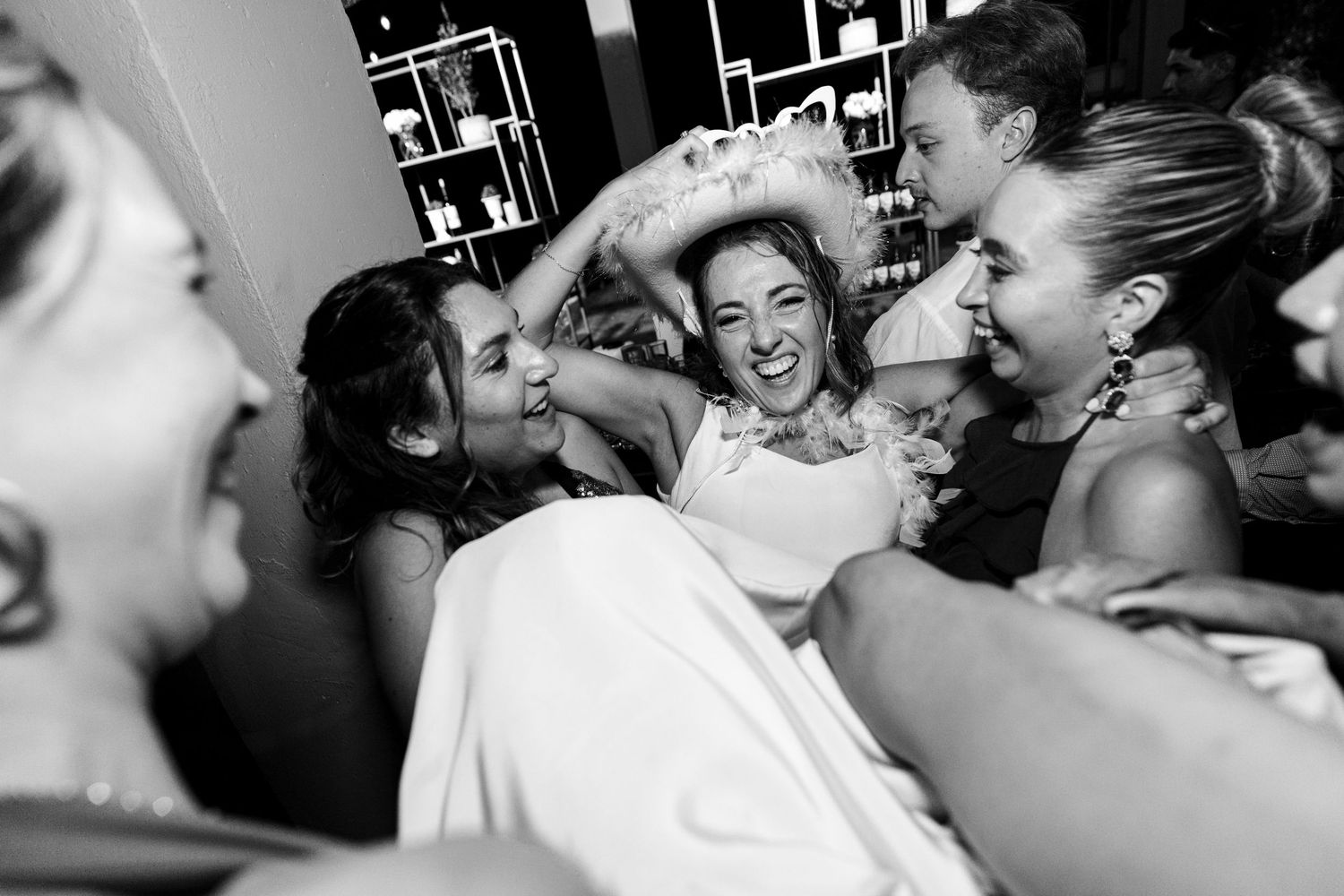 Wedding reception guests dancing close together under dim lighting at a lively party.