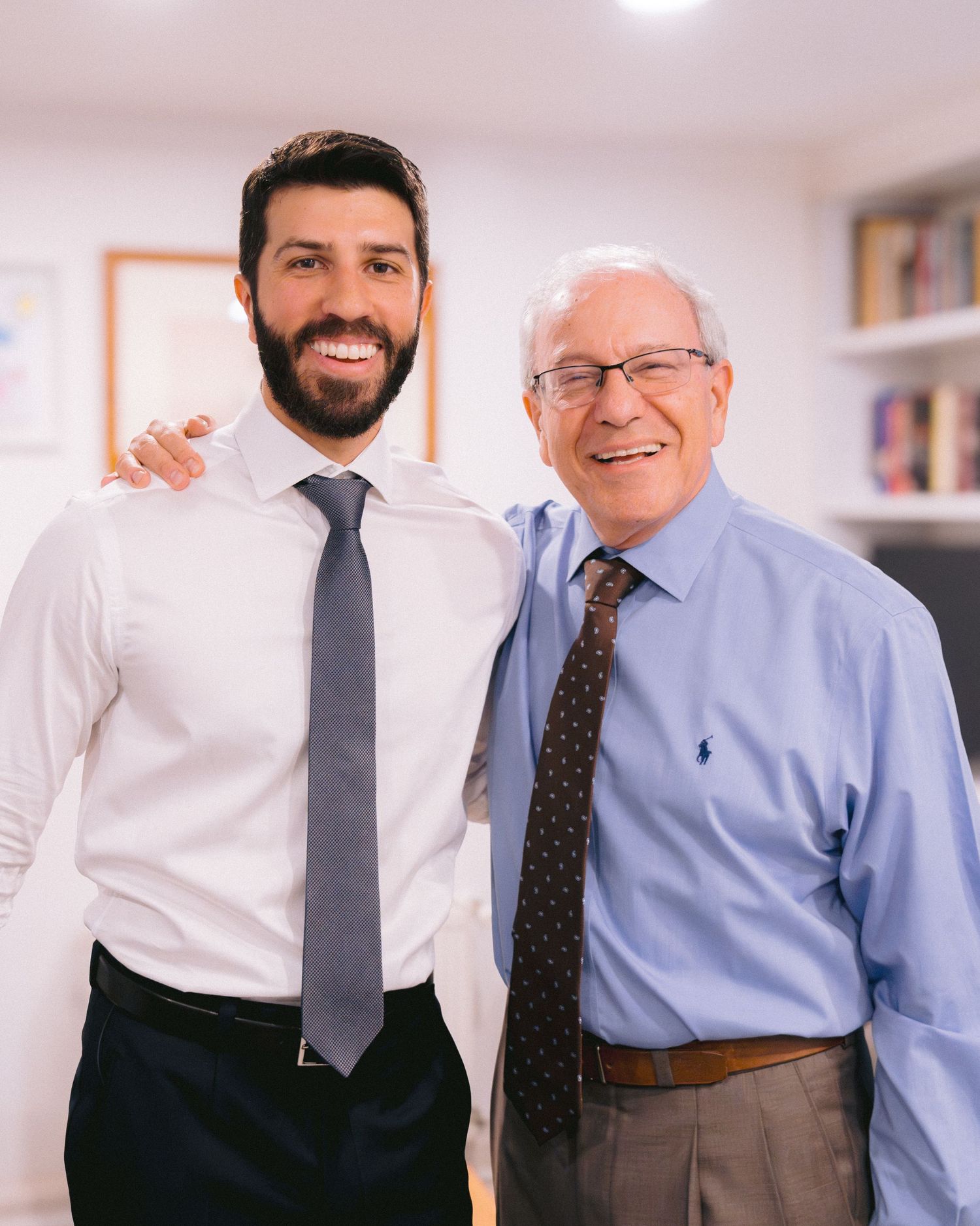 Two men in business attire standing together in an office setting.
