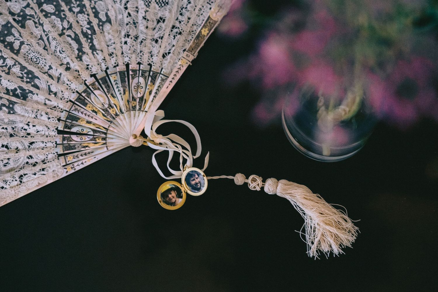 Delicate lace fan with intricate details photographed against a dark background.