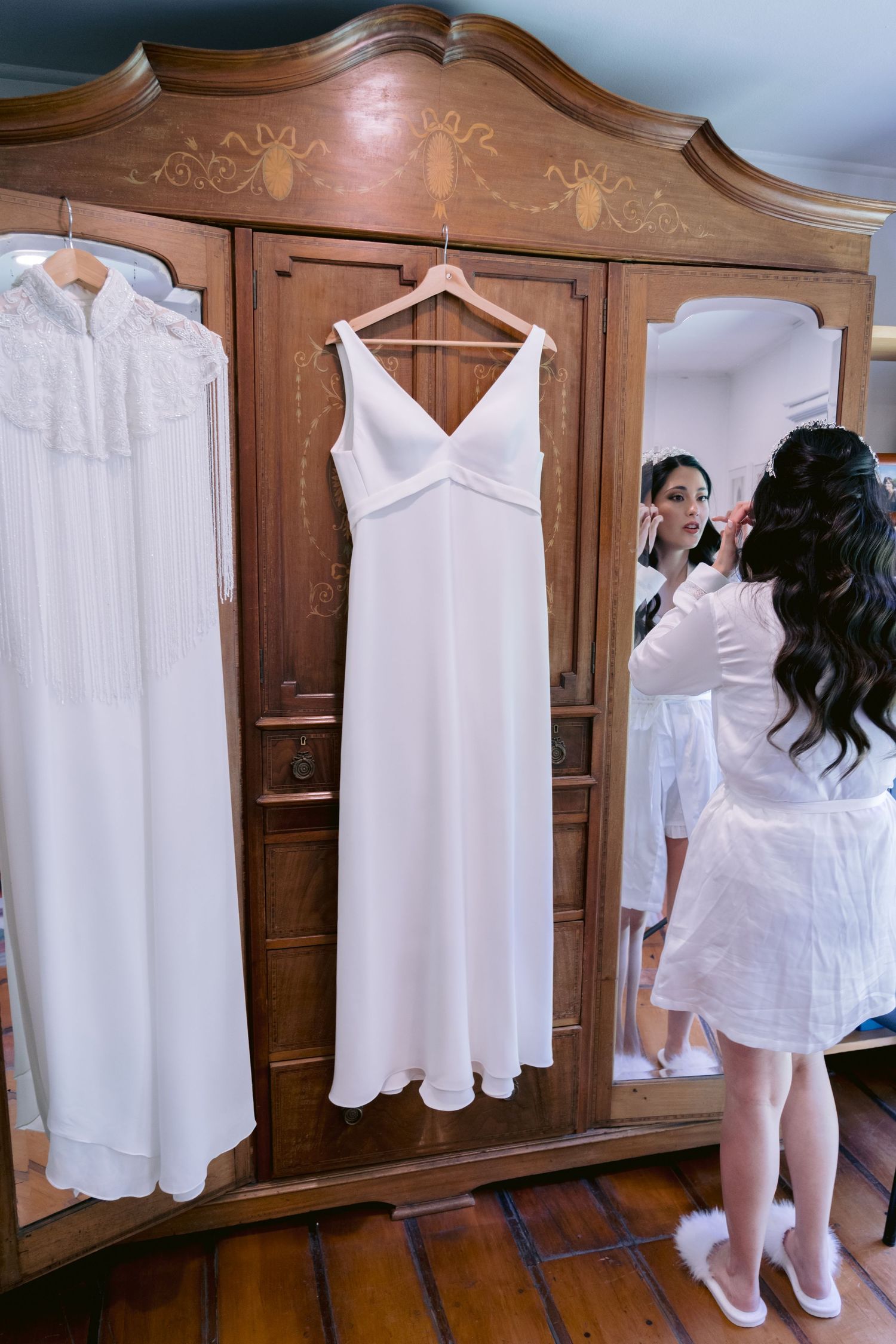 A sequence showing someone arranging white garments on hangers against a wooden wardrobe.