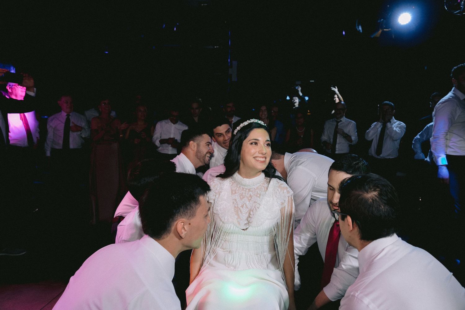 A lively dance floor scene with guests celebrating under purple and blue lighting effects.