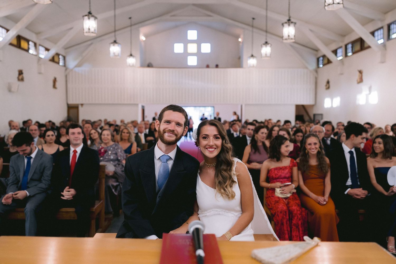 Large wedding ceremony in a bright white chapel filled with guests.