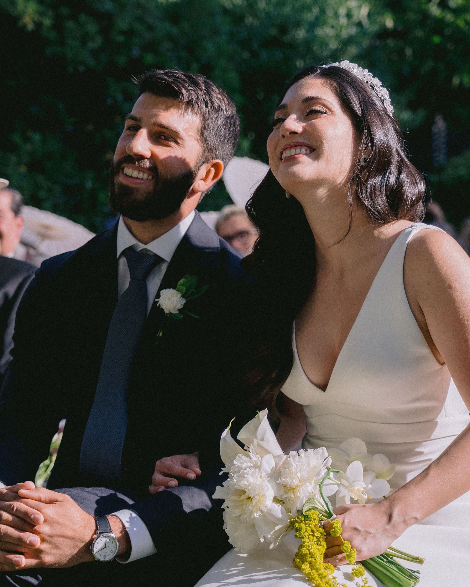 Candid outdoor wedding moment with couple and guests sharing laughter.