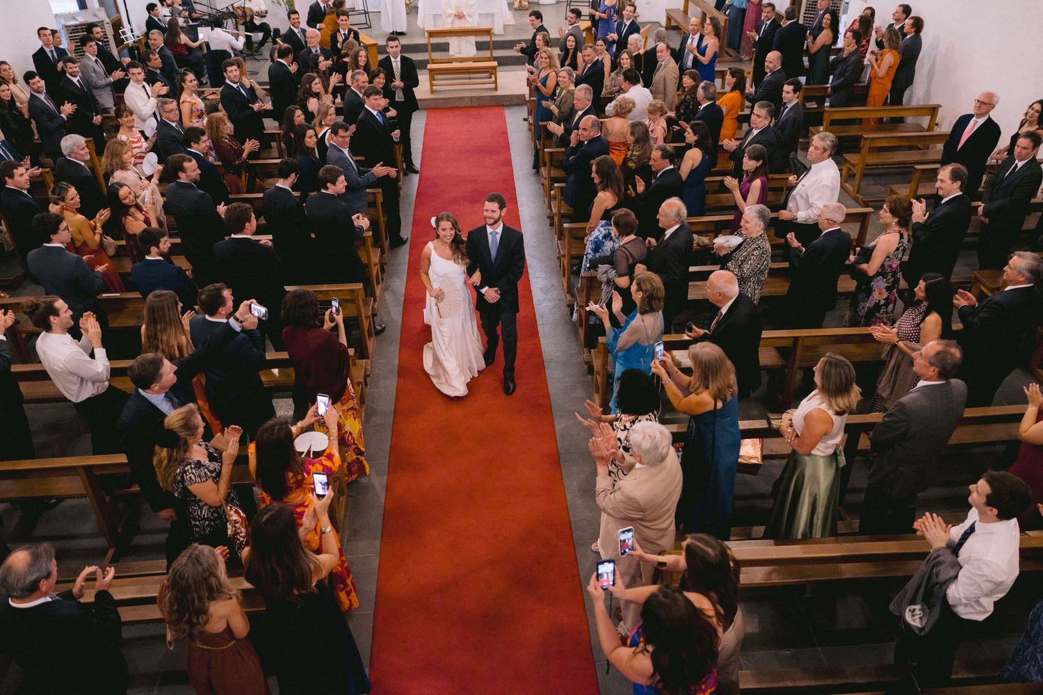 Large church gathering with guests seated in wooden pews during a ceremony.