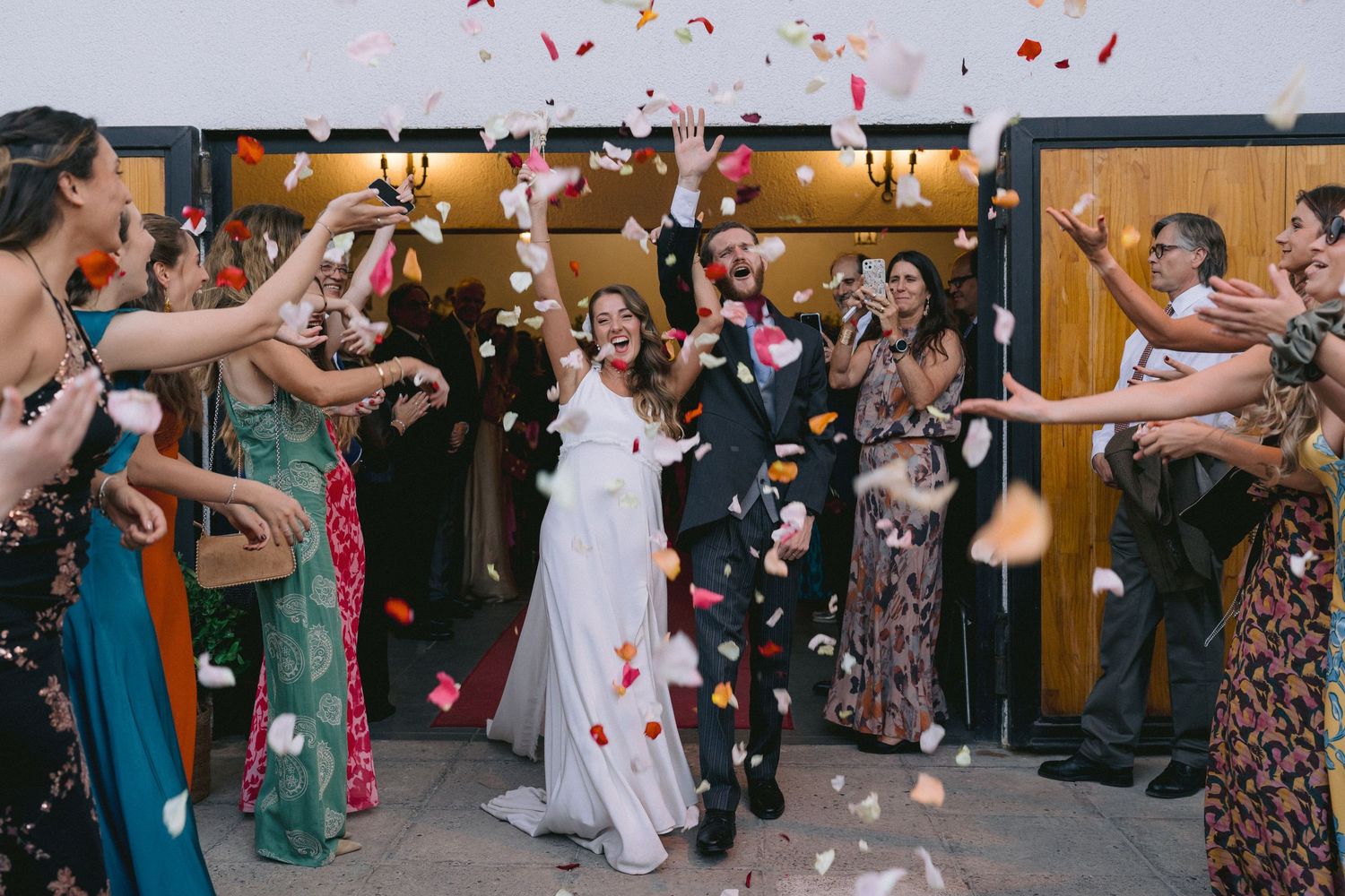 Wedding guests shower the newlyweds with red rose petals during their celebratory exit.