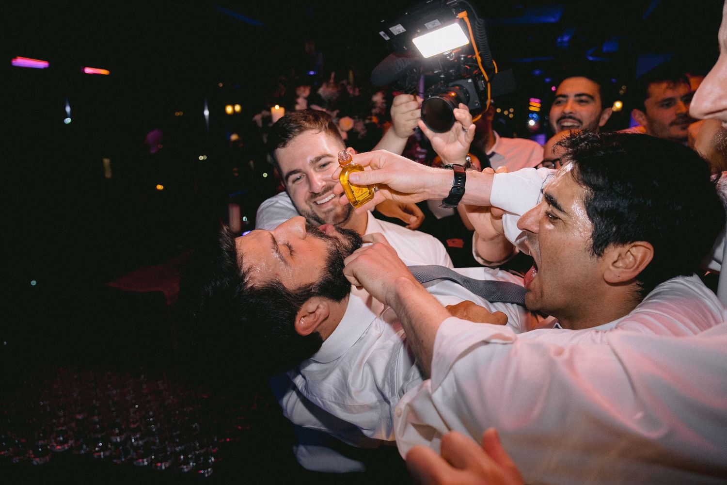 Party guests dance enthusiastically on a crowded dance floor under colorful lighting.