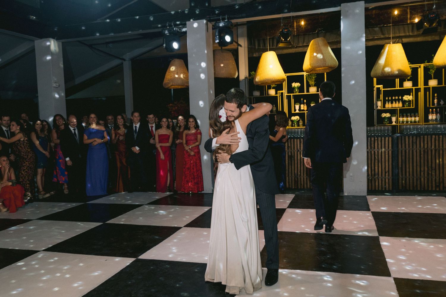Wedding venue interior with yellow lamp lighting and checkered dance floor setup.