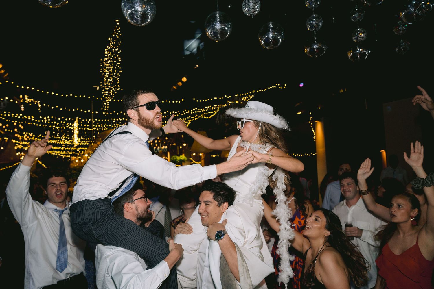 Dance party celebration with string lights and guests dancing in a lively atmosphere.