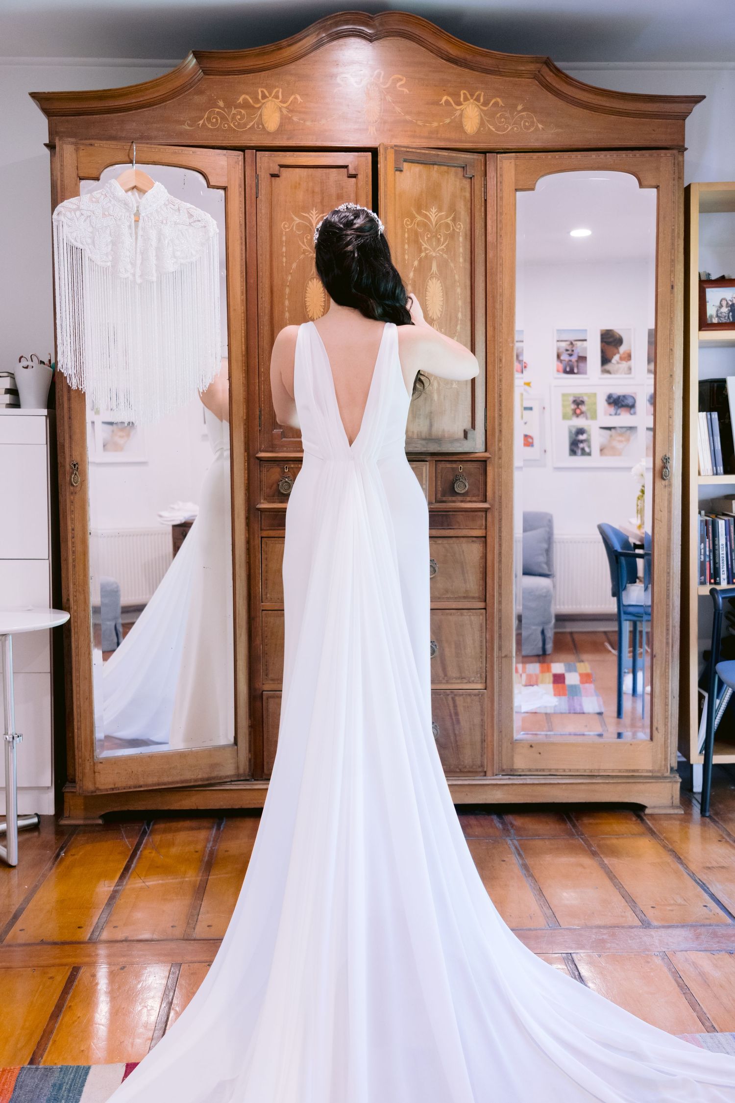 Wedding dress display with elegant white gowns hanging in front of wooden armoire mirrors.