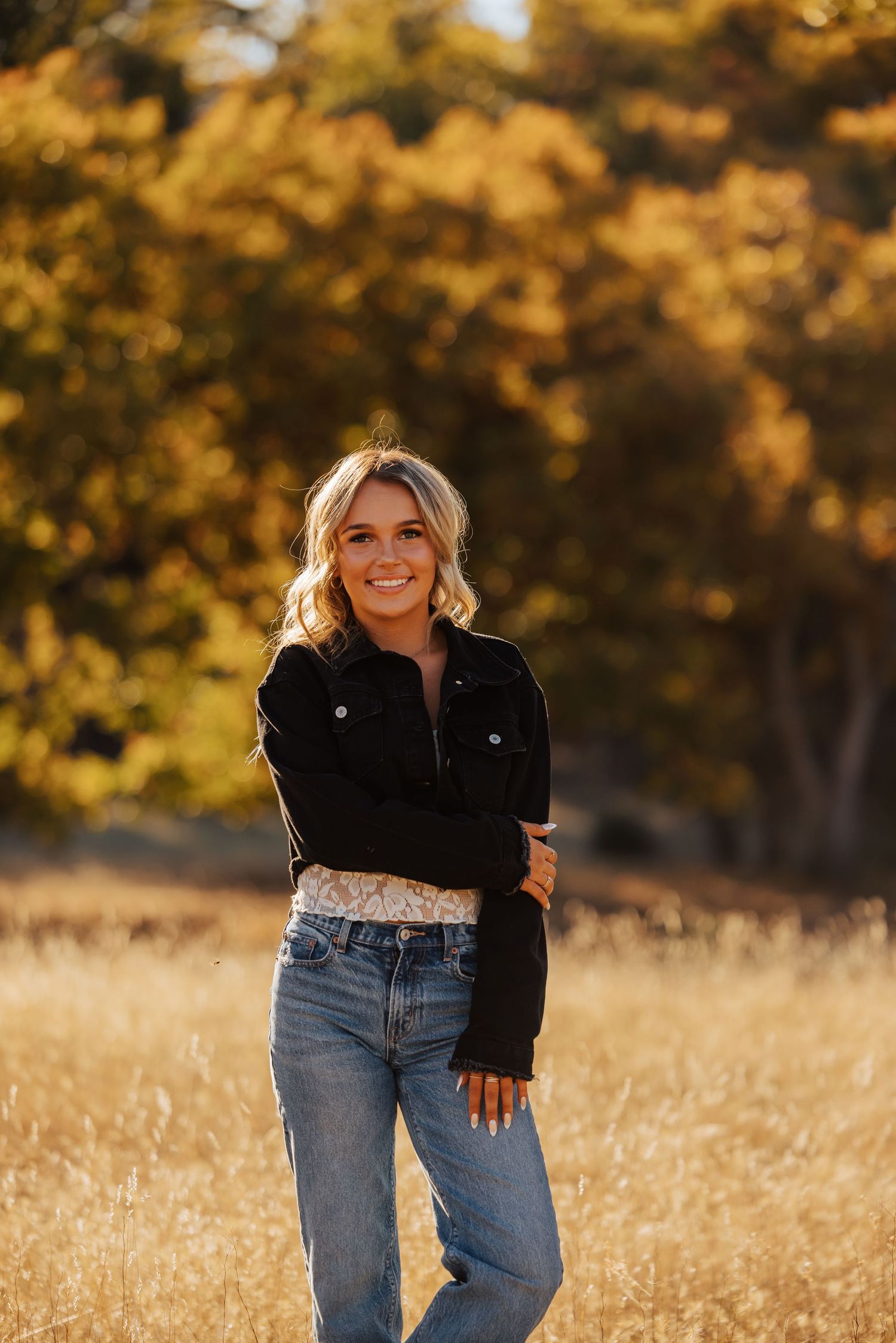 Casual fashion photography in a rustic field setting with fall foliage.