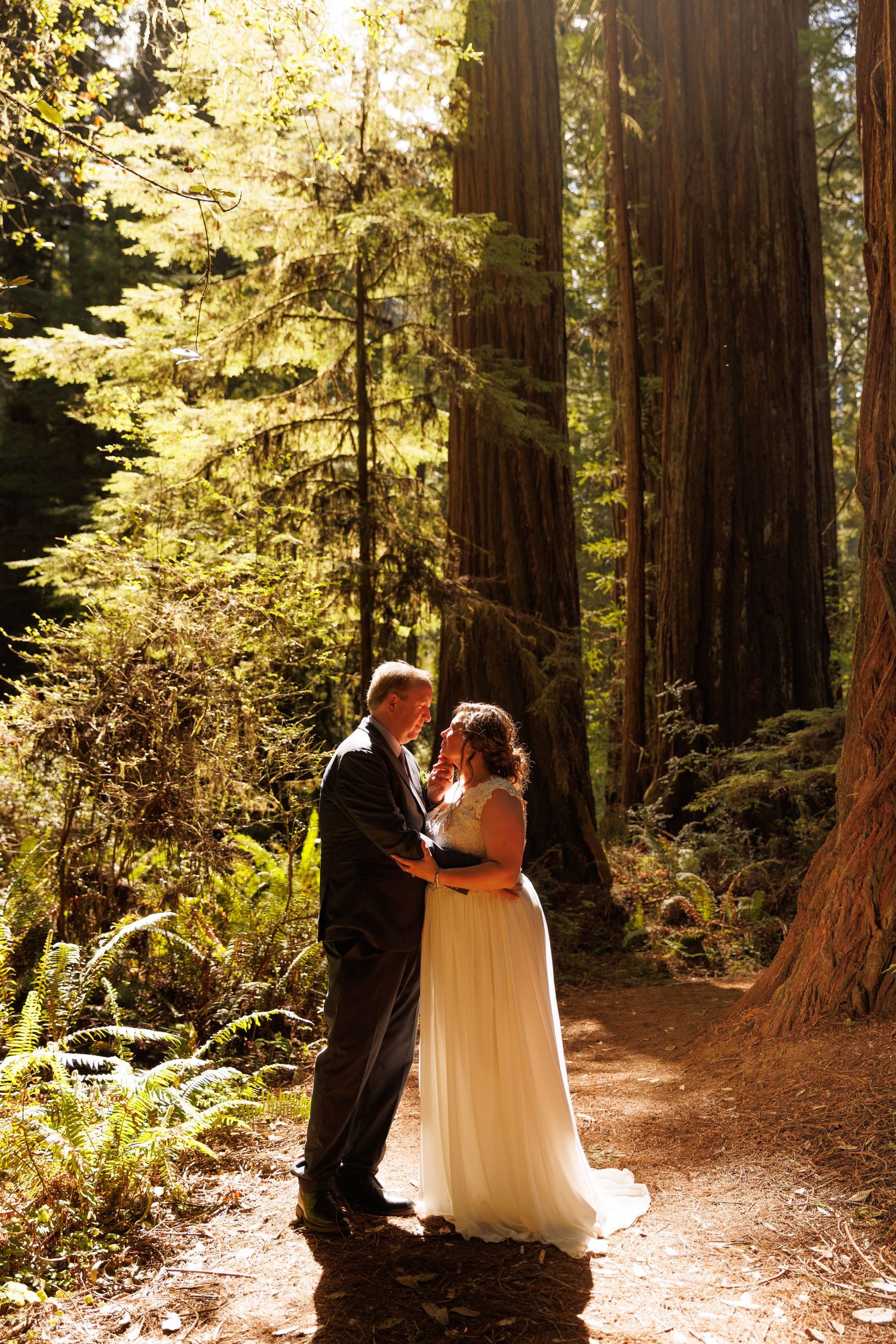 A romantic forest wedding scene with towering redwoods and dappled sunlight creating a magical atmosphere.