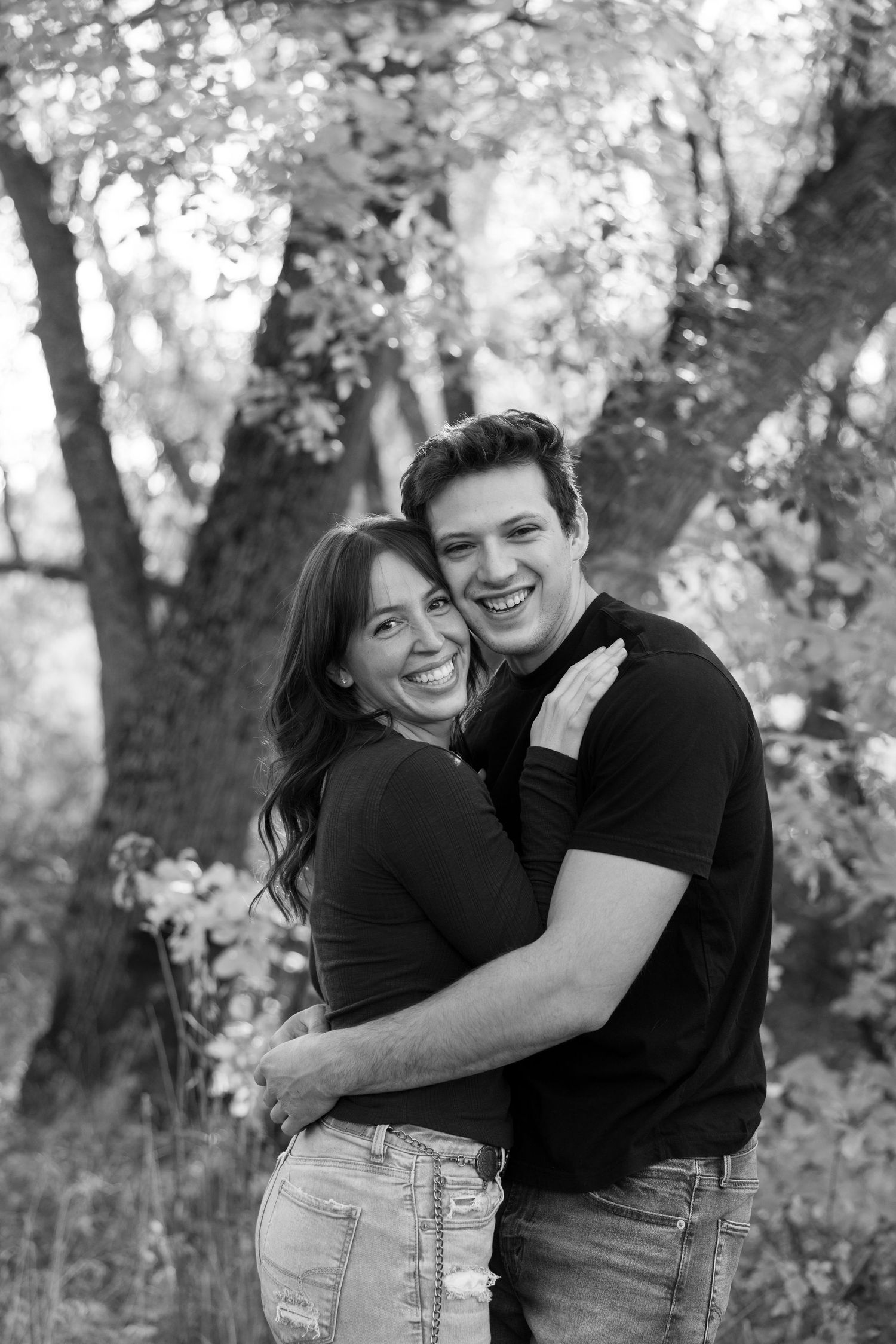 Black and white portrait of a couple sharing joyful laughter outdoors.