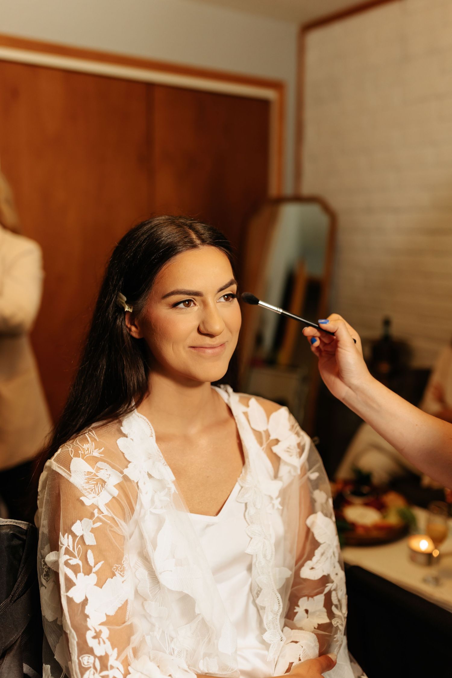 Makeup application during bridal preparation in warm lighting.