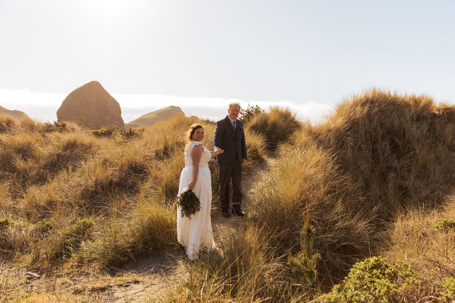 Golden sunlight illuminates a coastal wedding scene with dramatic cliffs and ocean views.
