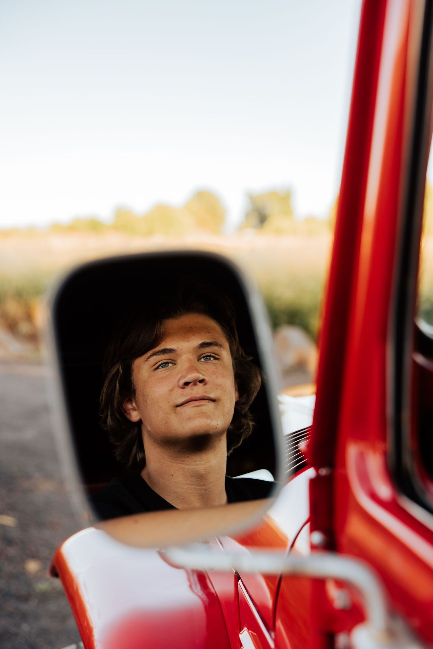 Person relaxing in red vintage car interior during sunset.