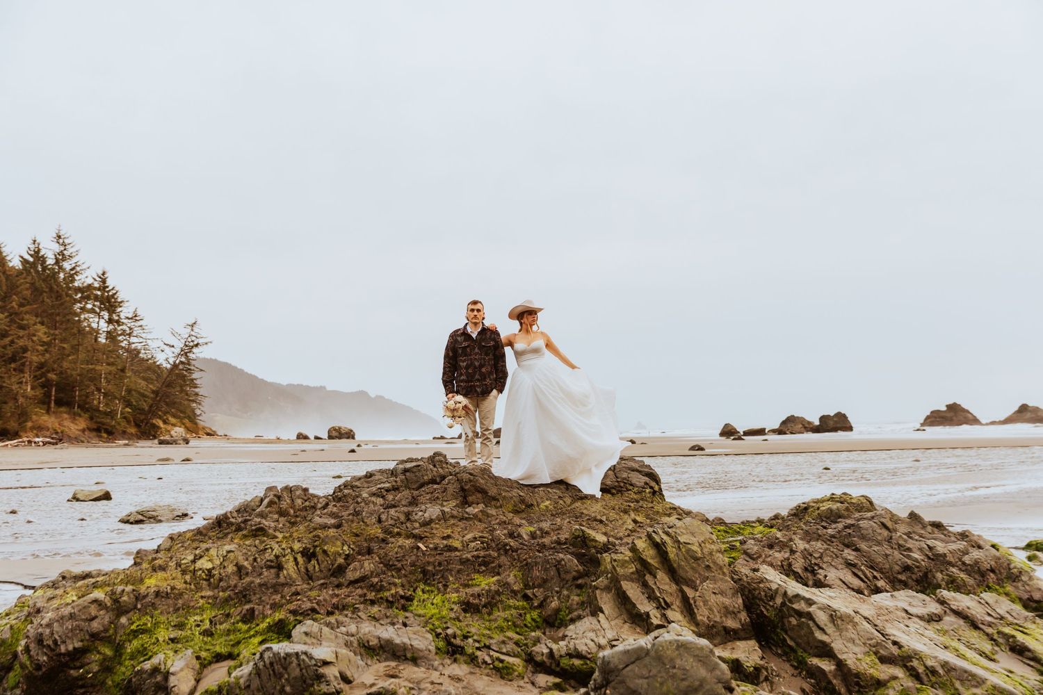 Dramatic coastal wedding photos captured on rocky cliffs overlooking the ocean.