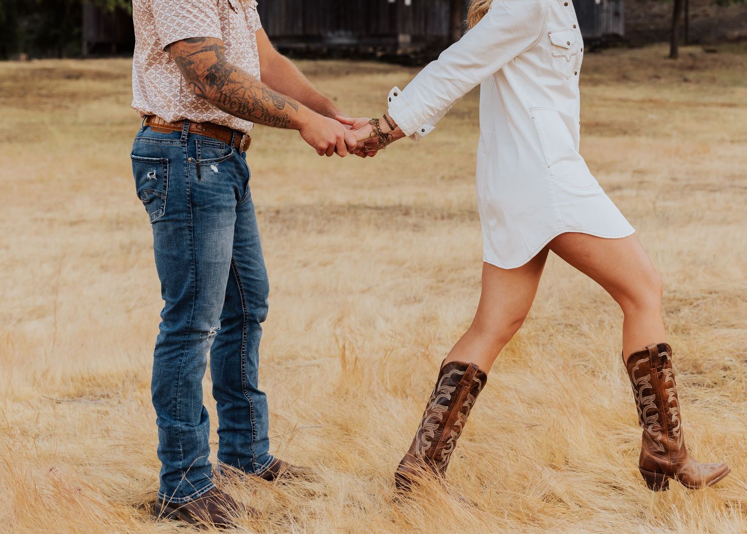 Dancing feet captured in motion against golden grass during a rustic outdoor photoshoot.