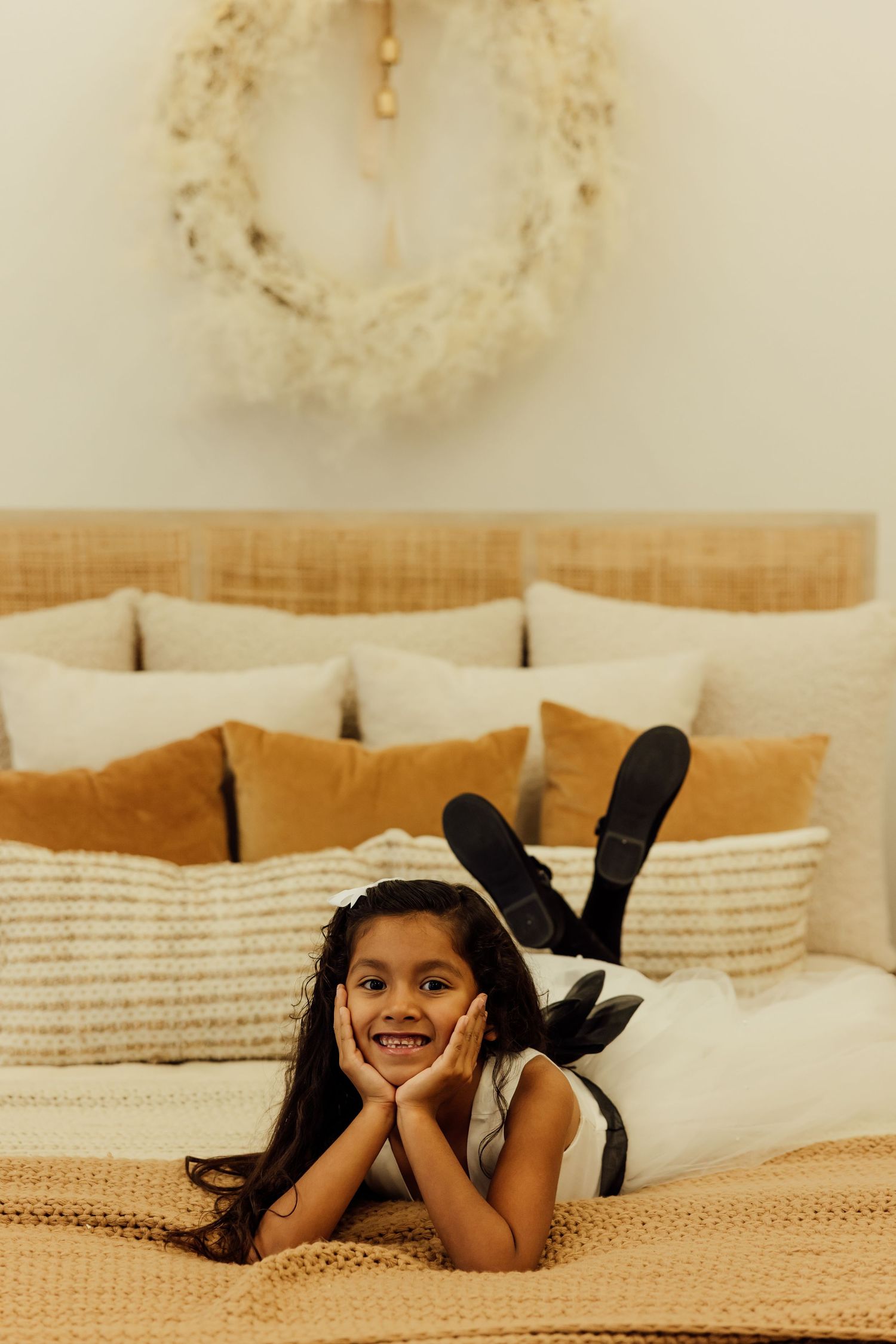 Young person lying on textured bedding with black ribbons in hair.