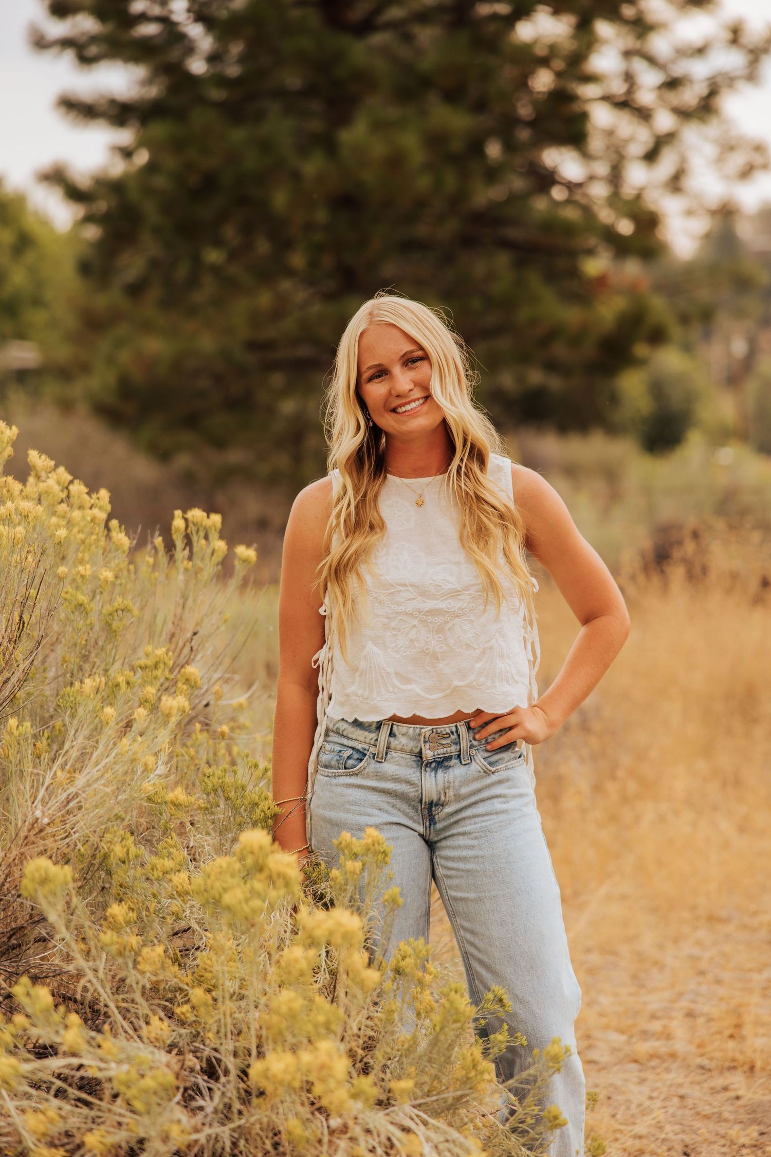 Summer fashion photography in a rustic field with light denim and white lace top.