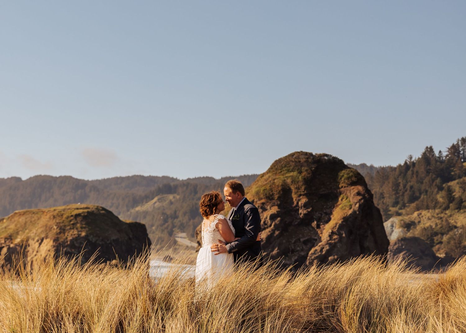 Dramatic coastal landscape with golden grass and rocky cliffs overlooking the Pacific Ocean.