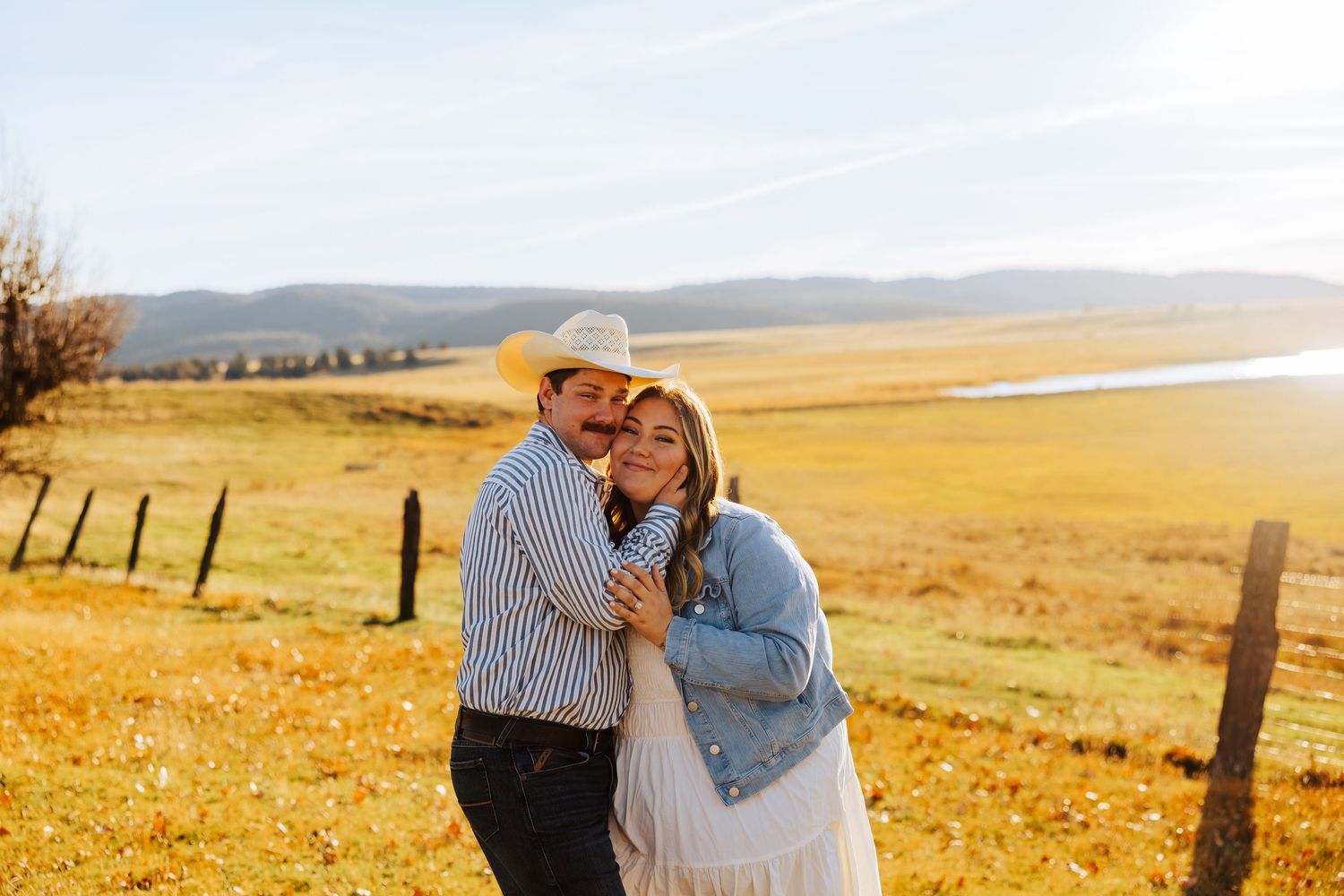 A couple shares tender moments against a backdrop of rolling hills and autumn fields.