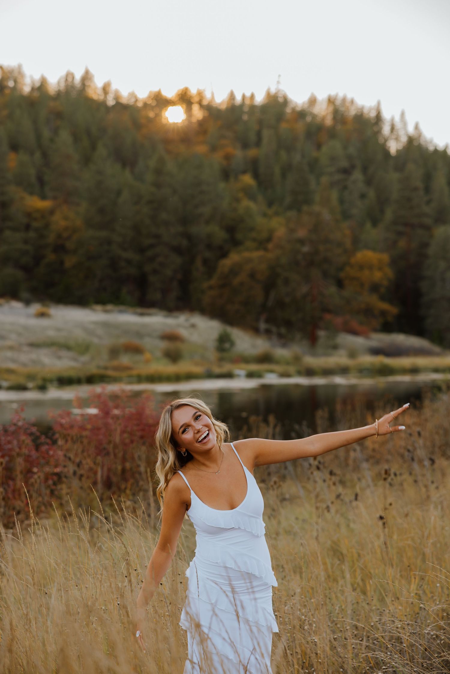 Joyful movement captured in a white dress against autumn scenery and evergreen trees.
