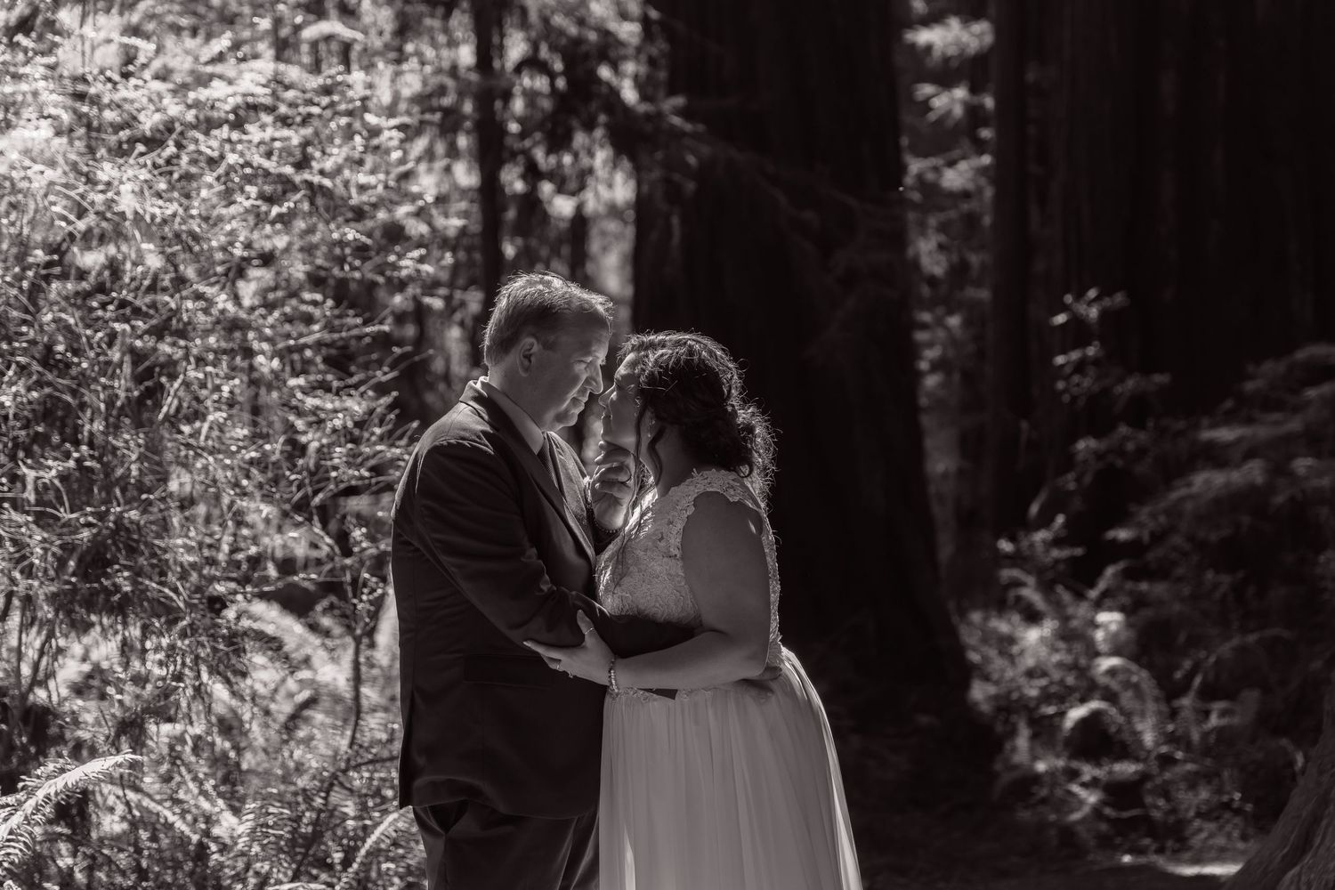 Black and white wedding portraits in forest setting with dramatic lighting.