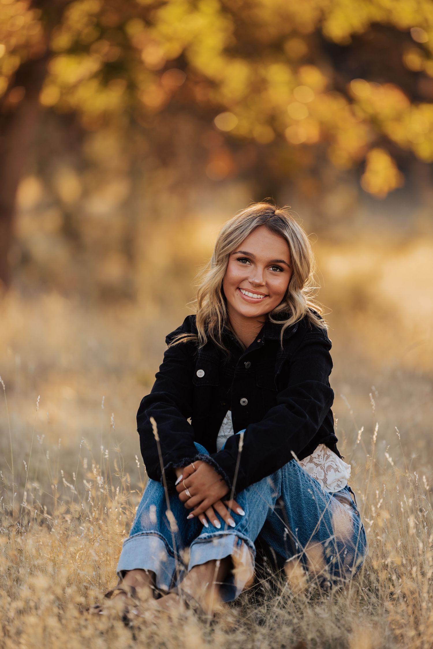 Casual outdoor photoshoot in a field during golden hour with fall foliage.