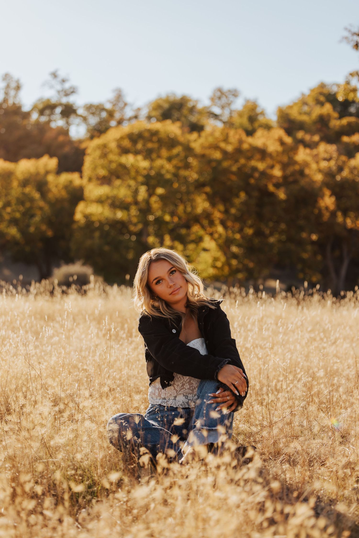 Artistic fall photography session in golden grass with natural lighting.