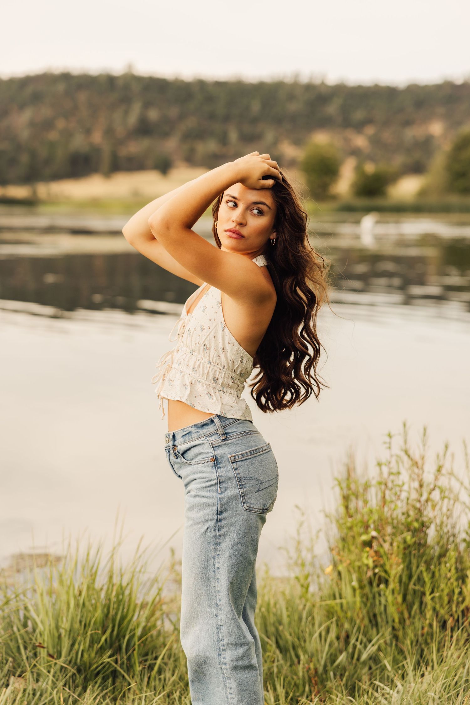 Artistic portrait session in a lakeside meadow with tall grasses during golden hour.
