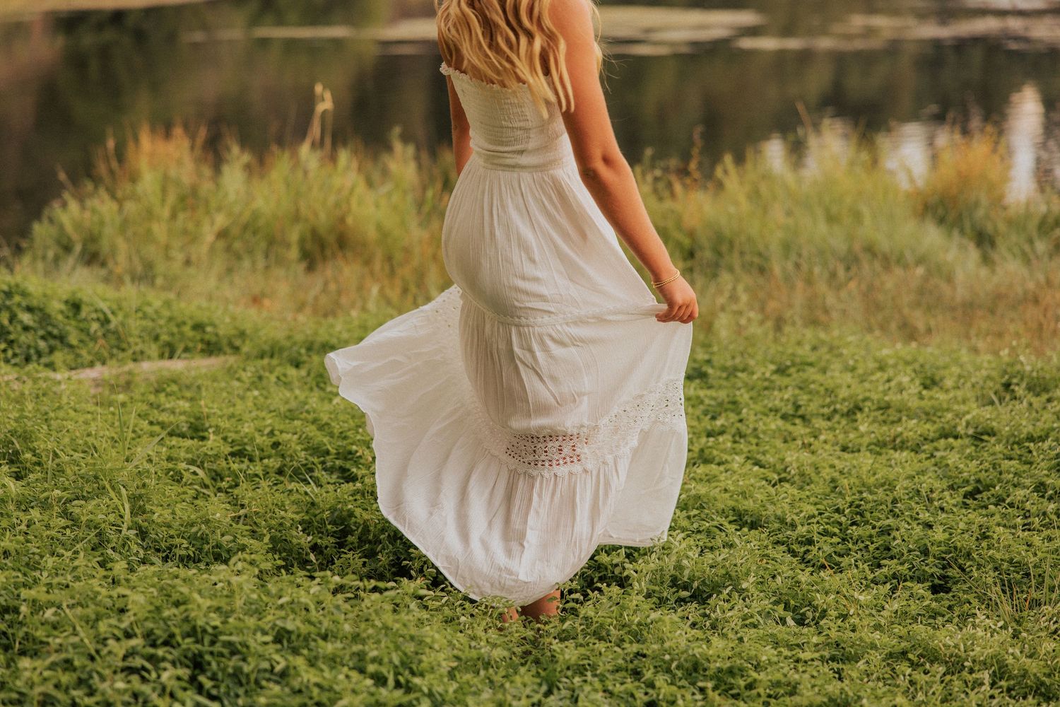 White dress twirling in motion against a natural outdoor setting with greenery.