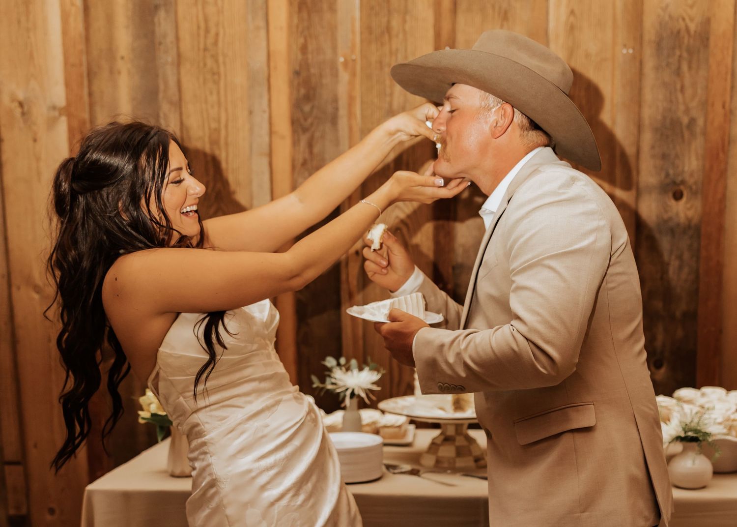 Playful cake cutting moment captured in warm indoor lighting with rustic decor.