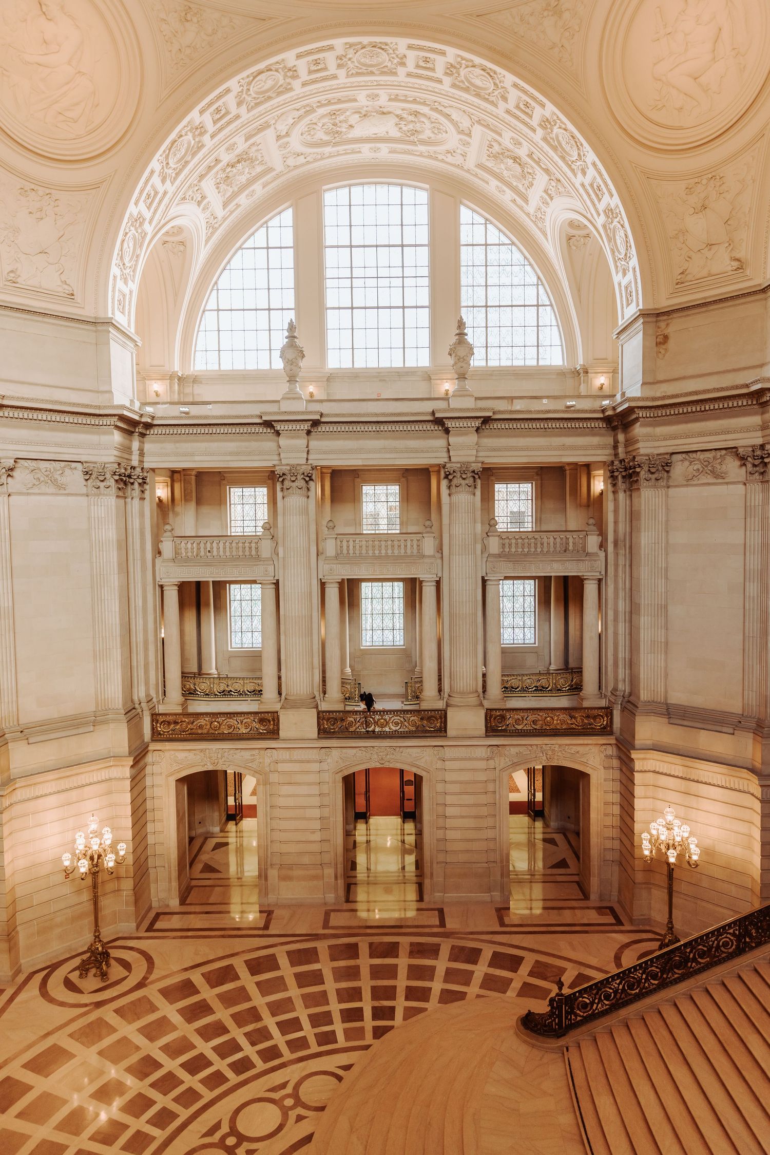 Ornate grand ballroom with arched windows, chandeliers and intricate architectural details showcases elegant classical design.
