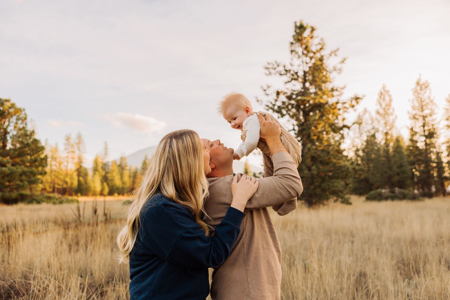 A joyful family moment captured in a mountain meadow during sunset.