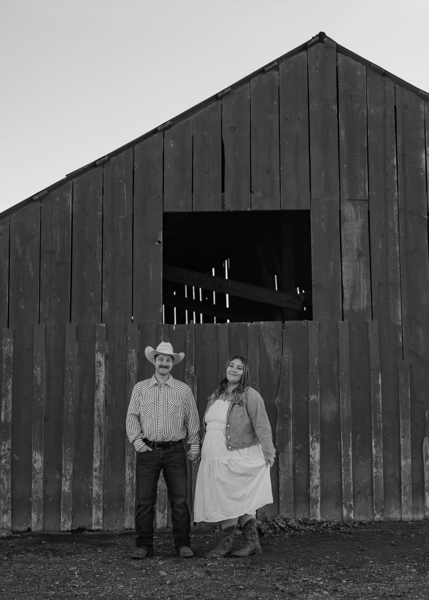 A series of silhouettes against a dark wooden barn in black and white photography.