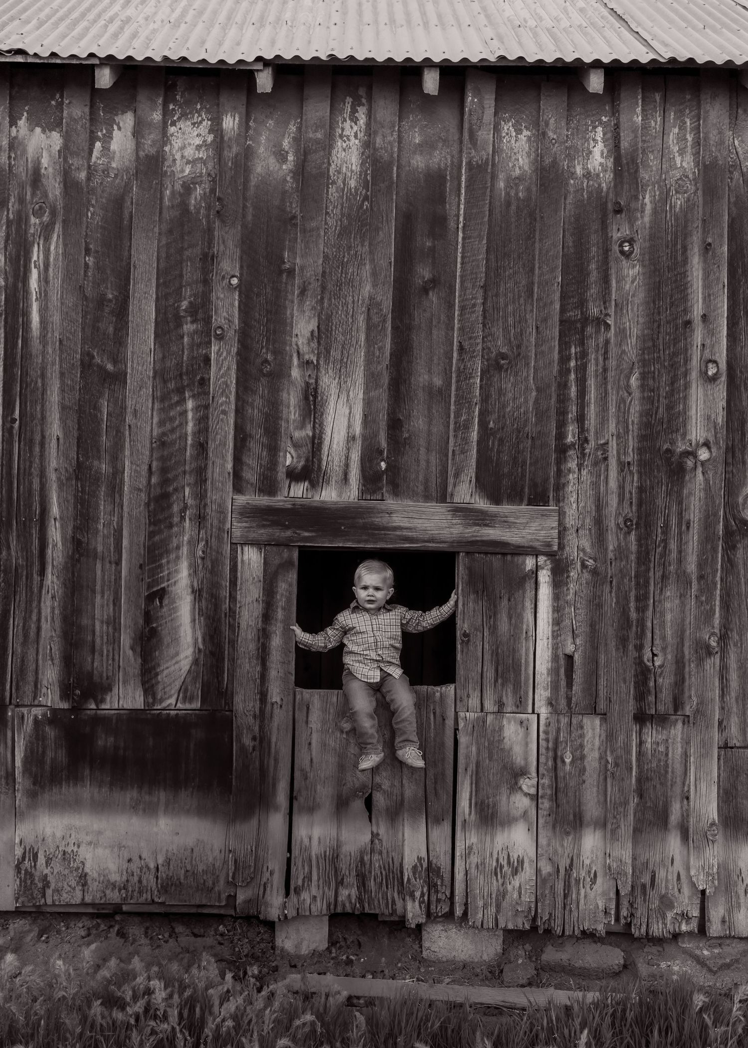 Black and white photo of old barn windows with rustic wooden siding.