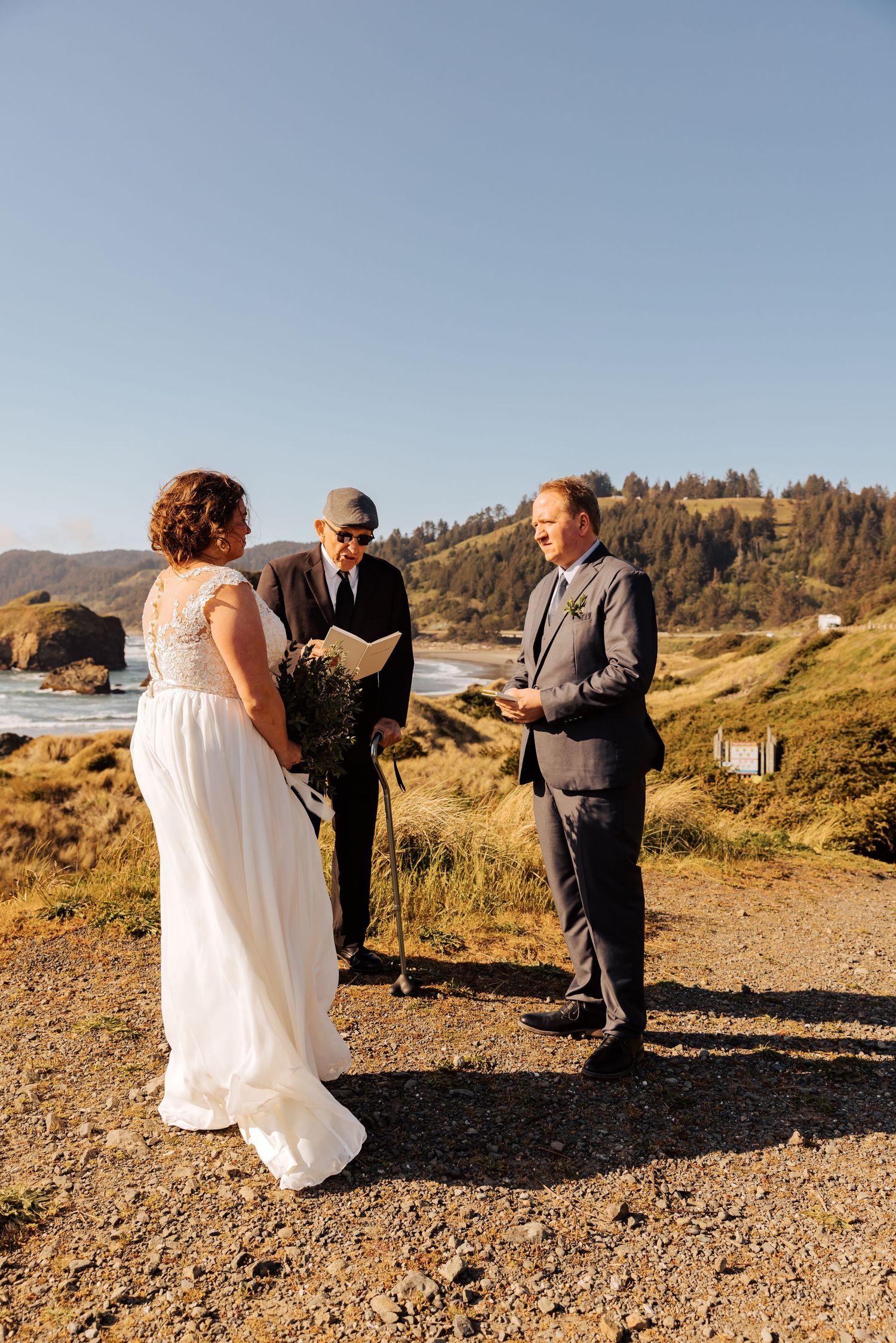 A small intimate wedding ceremony unfolds on a grassy cliff overlooking the Pacific coast.