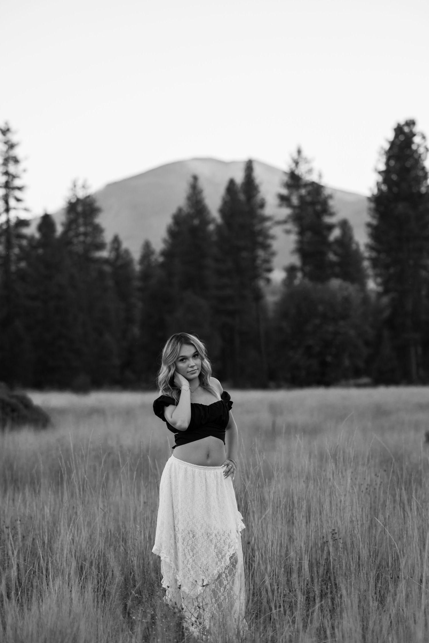Stylish outdoor portrait in two-piece outfit against mountain landscape in black and white.