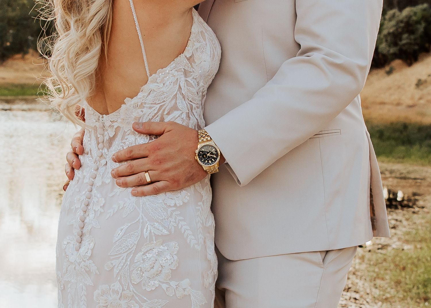 Close-up of elegant white lace wedding dress and light beige suit details.
