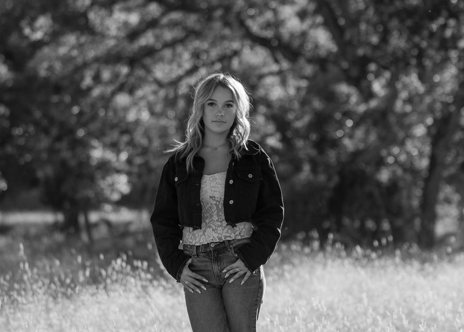 Black and white portrait session in a sunlit meadow with natural elements.