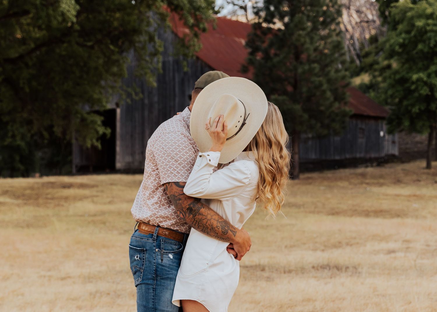 Dancing and twirling in a sun-drenched field with a rustic barn backdrop.
