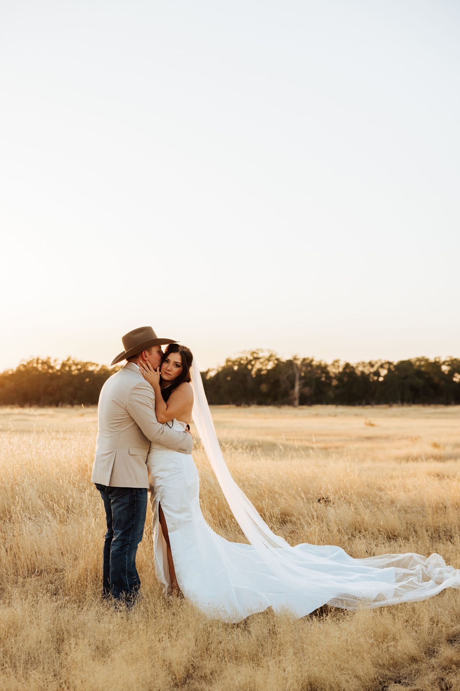 Romantic sunset portraits in a golden field with flowing white wedding dress.