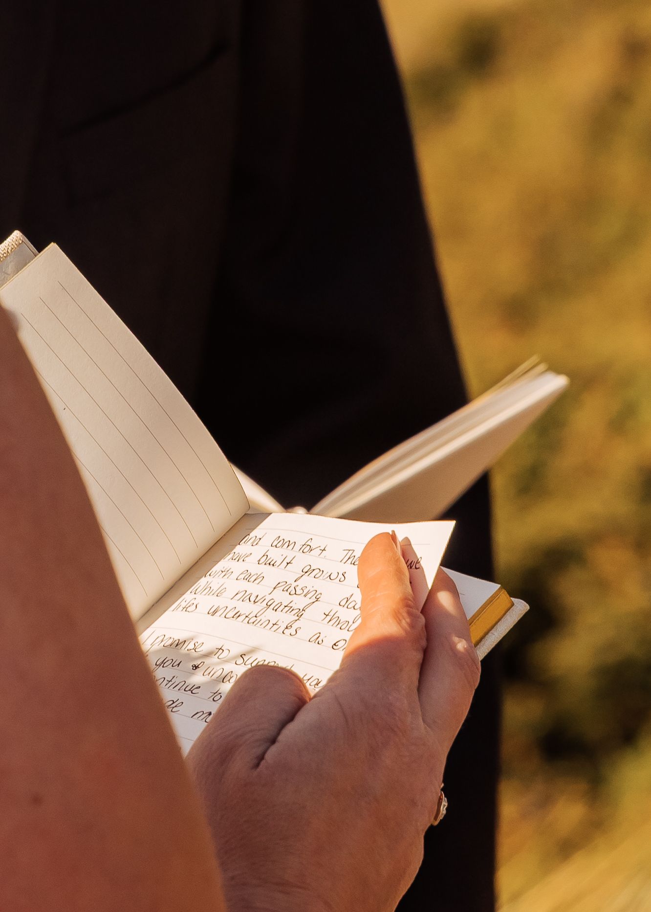 Handwritten vows being read from a small notebook during an outdoor ceremony.