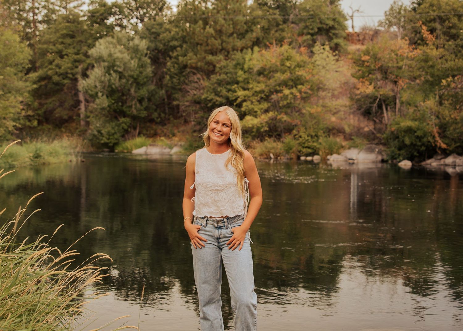 Lakeside photo session with casual denim outfit against natural scenery.