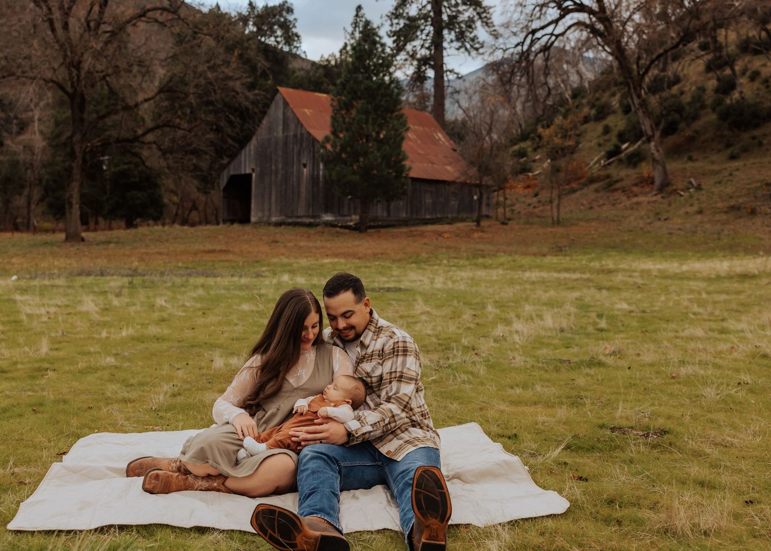 Relaxed family moment on picnic blanket in grassy field during sunset.