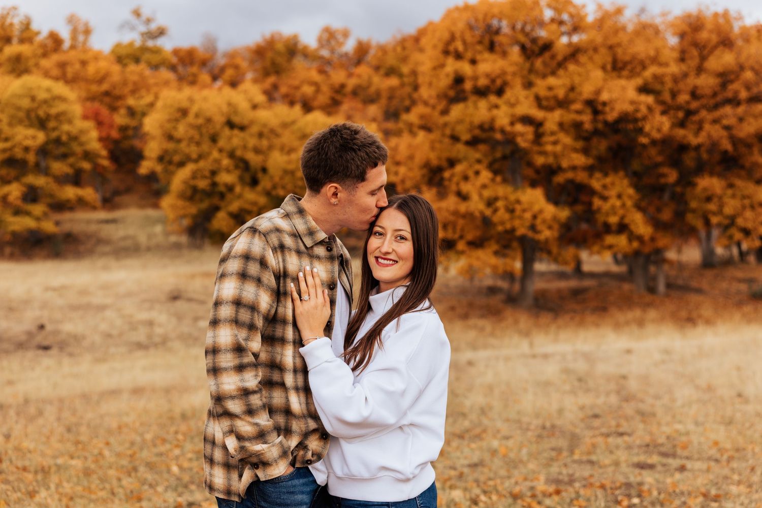 Romantic autumn engagement photos captured in a field with orange trees.