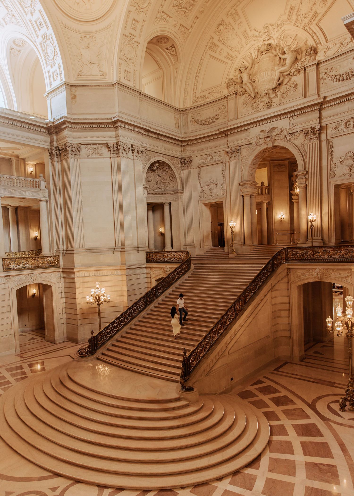 Grand marble staircase with curved steps and ornate architectural details in San Francisco City Hall's interior.